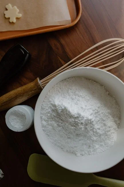 Box of powdered borax laundry booster next to a measuring spoon on a potting bench with green bean plants in the background