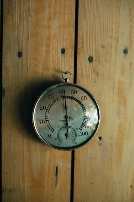 indoor wall thermometer reading above 90 degrees Fahrenheit in a dim overheated bedroom
