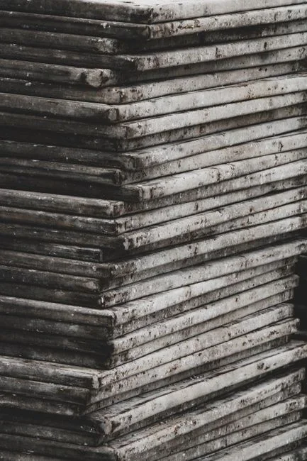 Stack of stiff faded worn cotton bath towels folded on a laundry room shelf