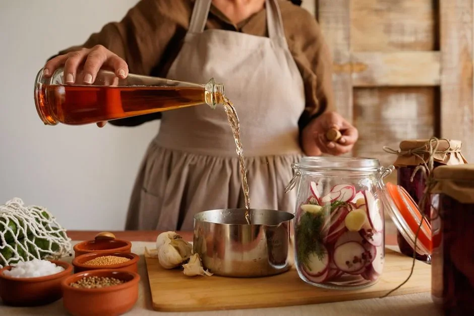 Pouring white vinegar from a glass measuring cup into a front-load washing machine detergent drawer