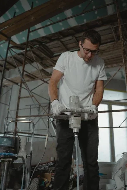 A person using a caulking gun to seal a gap around the frame of an attic gable vent to keep overwintering flies out