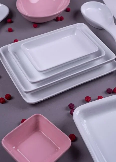 Shallow white dish of soapy water on the floor under a small glowing bedside lamp at night in a dim bedroom
