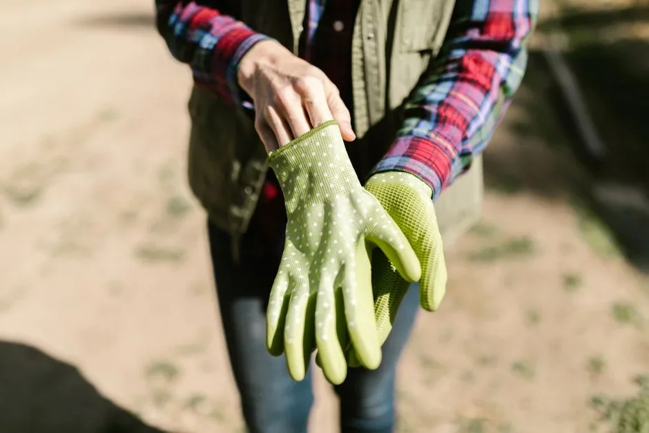 gardener wearing safety goggles and chemical resistant gloves spraying weeds with a pump sprayer
