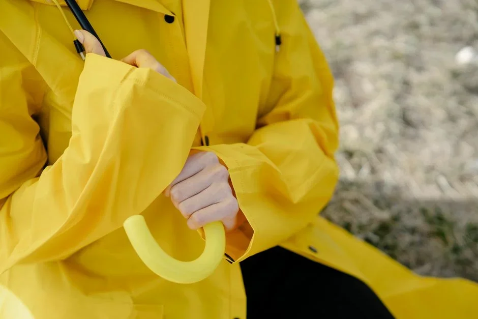 Hands wearing waterproof rubber gloves and safety glasses mixing wet gray concrete in a bucket
