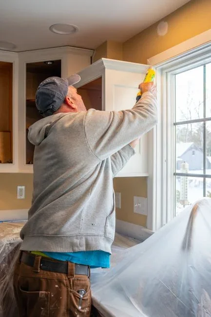 Homeowner applying a bead of caulk with a caulking gun to the gap between exterior window trim and siding on a house in early autumn