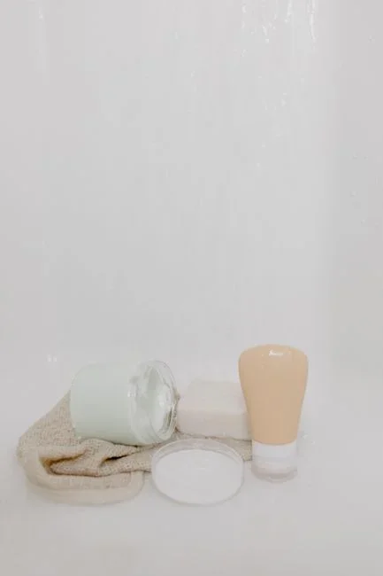 Bathroom counter with a bar of soap, a washcloth, a bottle of calamine lotion and a tube of hydrocortisone next to a running shower
