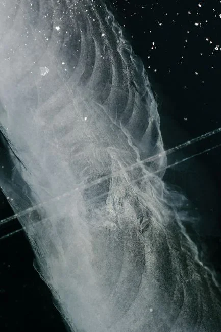 Thick white ice coating the copper refrigerant line and evaporator coil housing of an indoor air handler in a basement