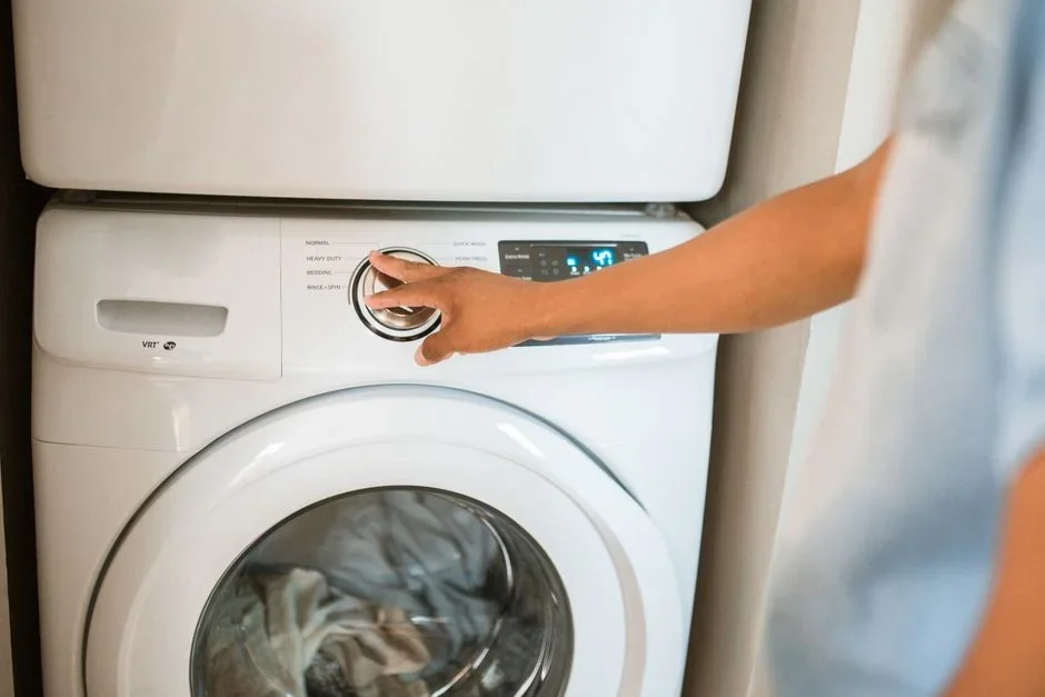 Close-up of a hand peeling a thick gray mat of lint off a dryer lint screen filter in a home laundry room