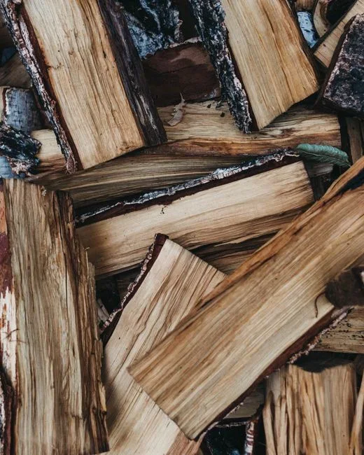 Aerosol insecticide can being sprayed onto a stack of split firewood, a practice extension services warn against