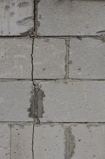 Horizontal crack across a concrete block basement wall with the blocks visibly bowing inward and white efflorescence staining