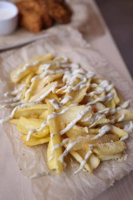 Two batches of homemade potato chips side by side on parchment paper, one pale golden and evenly cooked, the other dark brown and blotchy