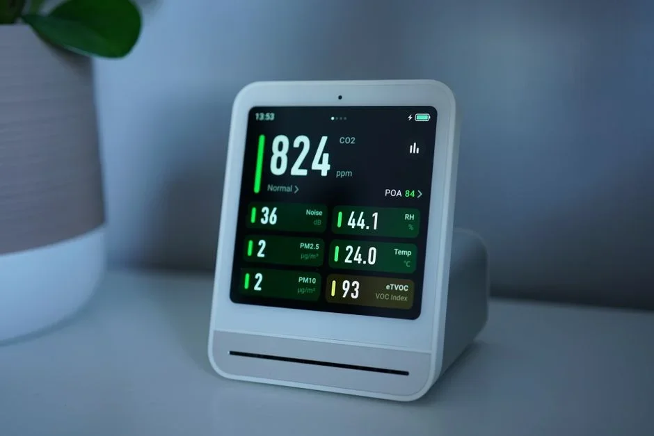 Small dehumidifier running on a concrete basement floor next to a digital humidity monitor