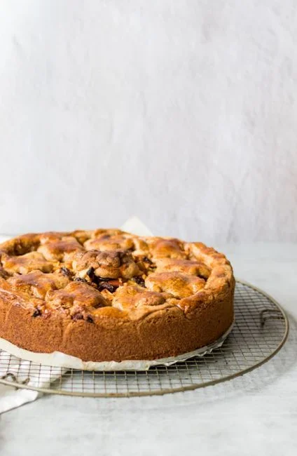 Sliced apple rings and halved apricots in a single layer on a wire rack inside a home oven with the door propped open a few inches