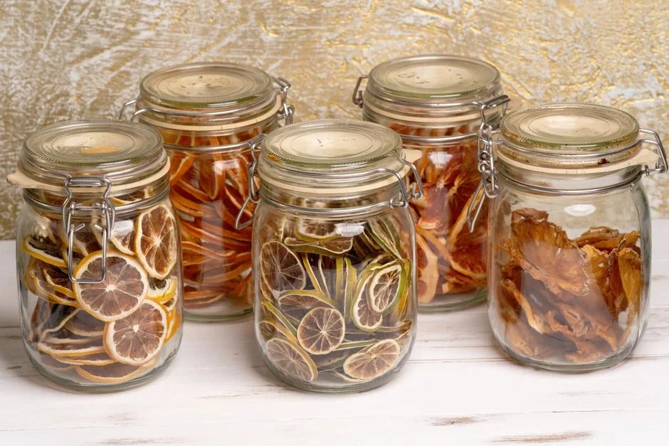 Glass mason jars packed loosely with dried apple slices on a kitchen counter, one jar showing condensation on the inside of the glass