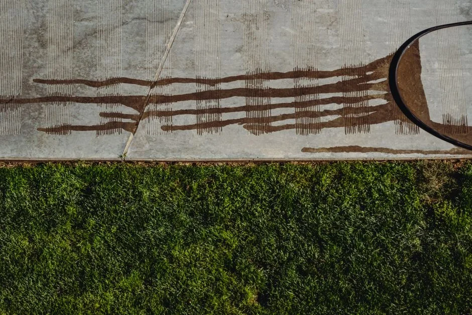 Oil-stained shop rags and a solvent-soaked cloth spread flat outdoors on a concrete driveway to dry safely