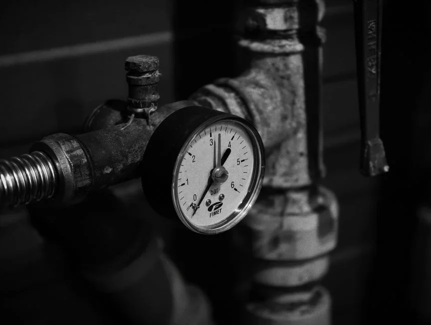Close-up of a pressure canner dial gauge reading eleven pounds of pressure with steam rising from the vent pipe