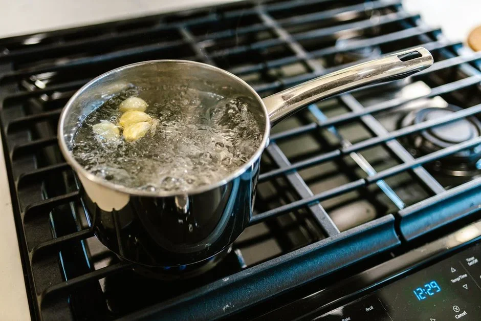 Pot of home-canned green beans boiling on a stove with a kitchen timer set beside it