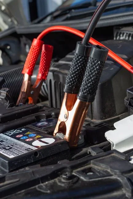 Close-up of a car battery positive terminal covered in blue-white corrosion crust with the cable clamp still attached