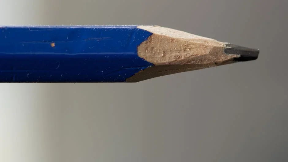 Hand touching the tip of a wooden pencil to a pane of glass, showing the gap between the pencil point and its reflection