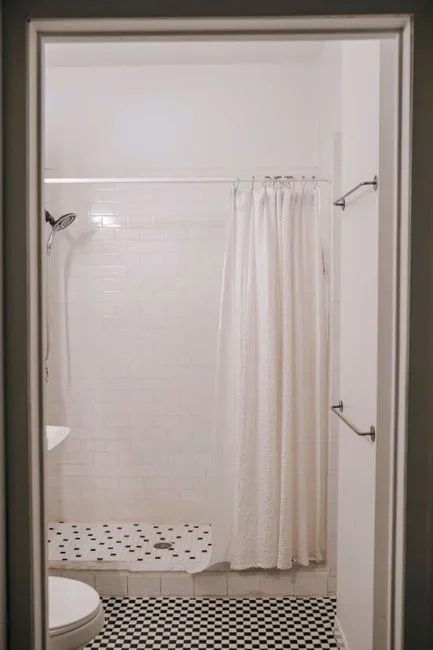 Silverfish insect crawling on white bathroom tile floor near the base of a shower at night