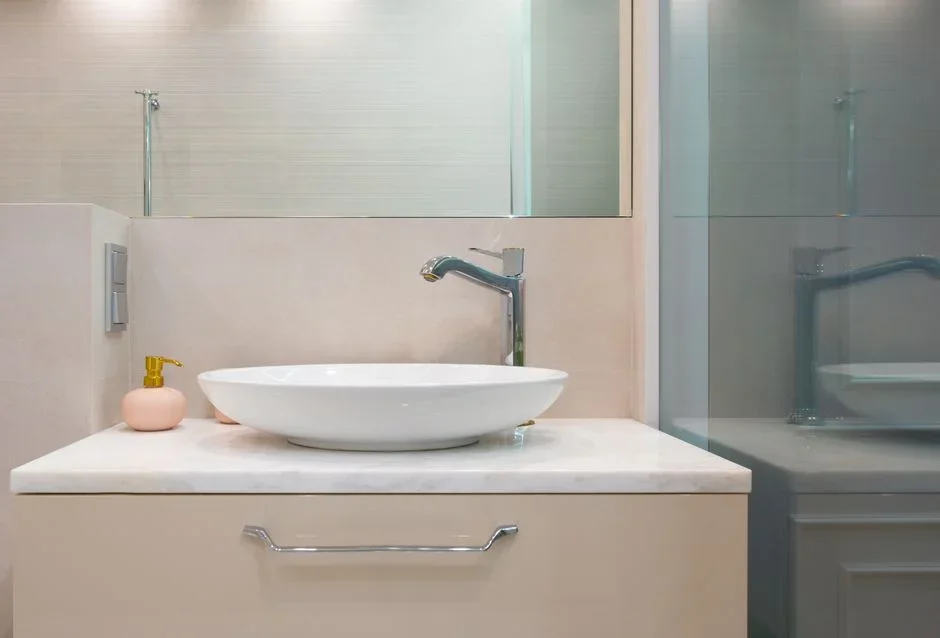 Digital hygrometer displaying relative humidity percentage on a bathroom counter beside a sink