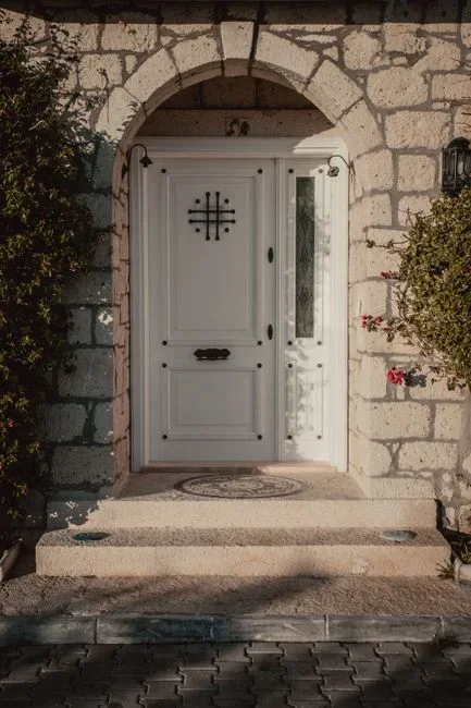 Close-up of daylight showing through the gap beneath a closed exterior door with a new door sweep and screws lying on the threshold